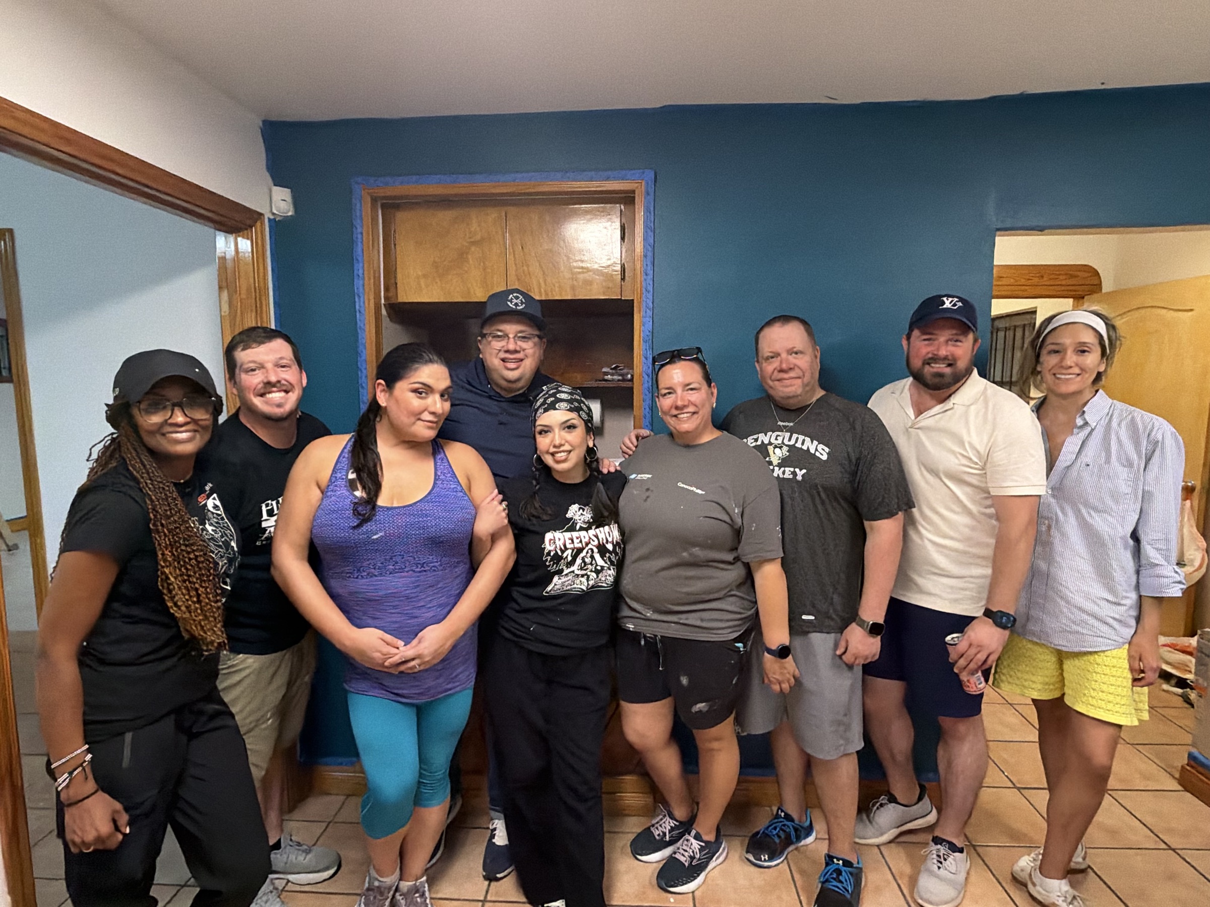 Volunteers and board members in front of the freshly painted teal wall at The Mosaic Center