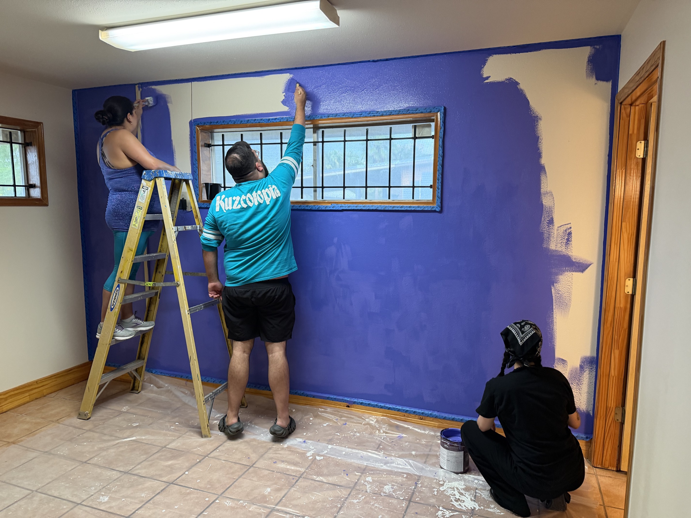 Three volunteers painting the purple room