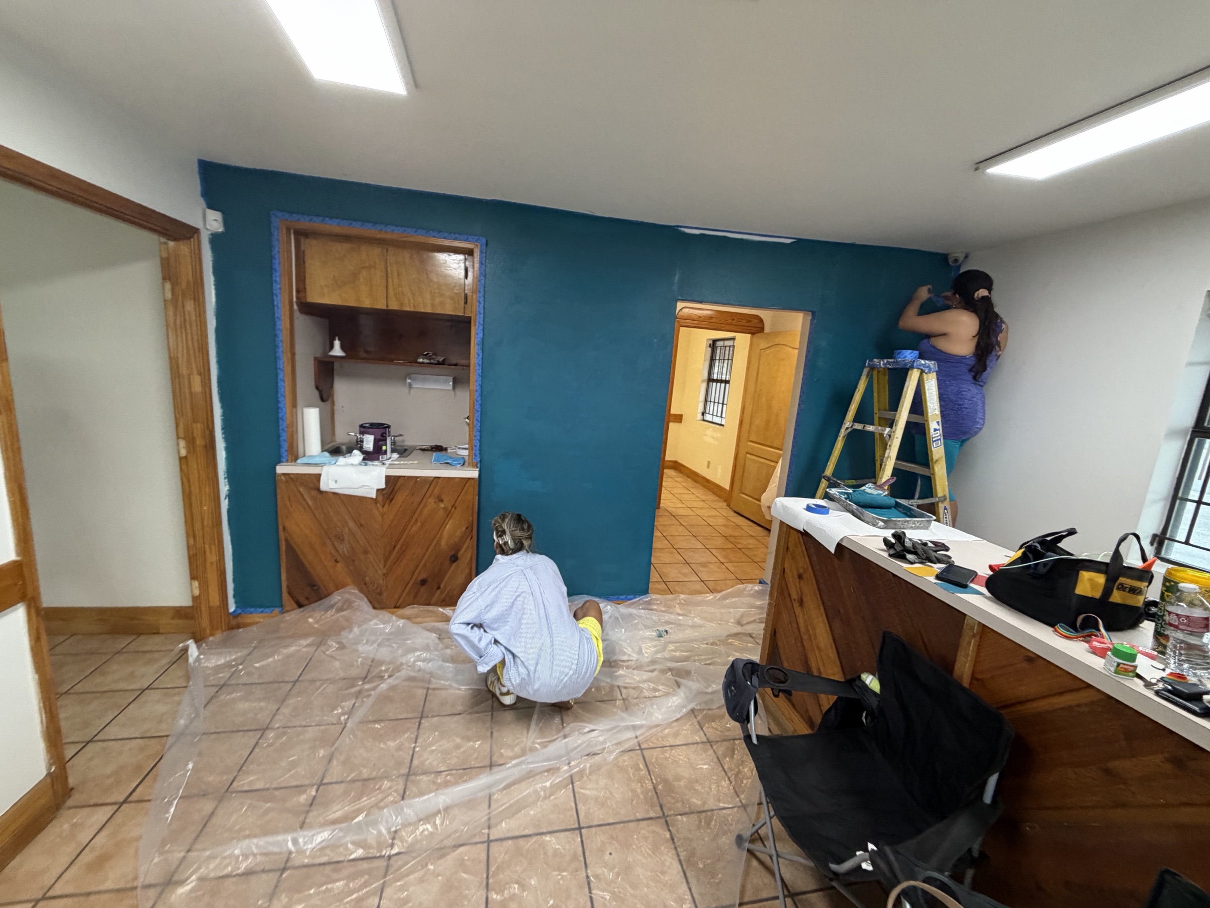 The main room of The Mosaic Center mid-paint, teal wall and wood counter