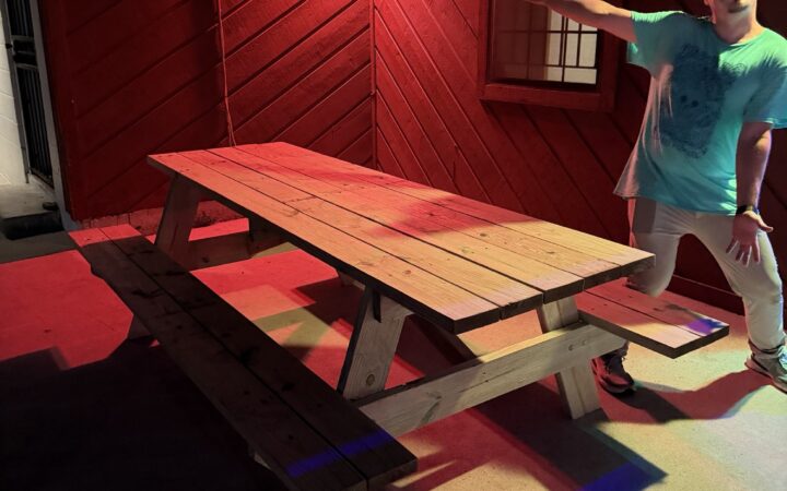 A new handmade wooden picnic table on the Center's patio under red lights