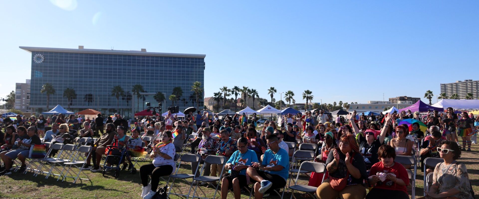 The block party crowd on the bayfront lawn, palm trees and blue sky behind