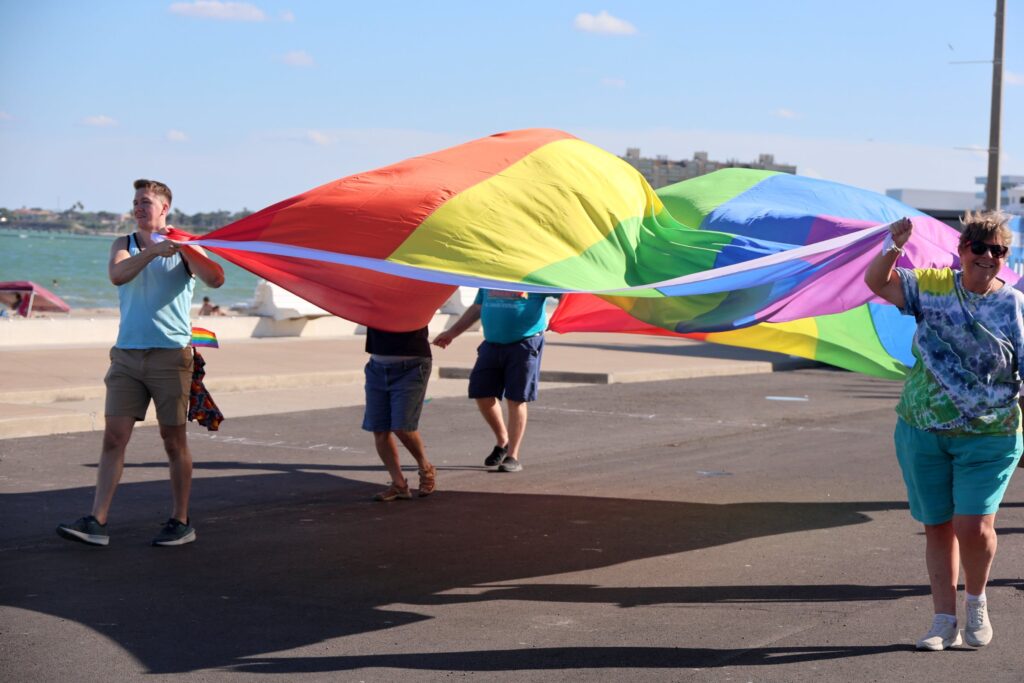 Volunteers carrying a giant rainbow flag along the bayfront