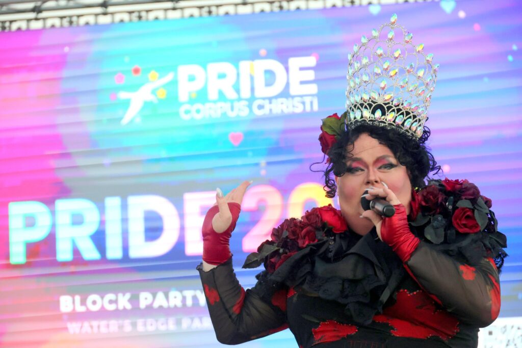A queen in a jeweled crown performing on the Pride 2026 main stage
